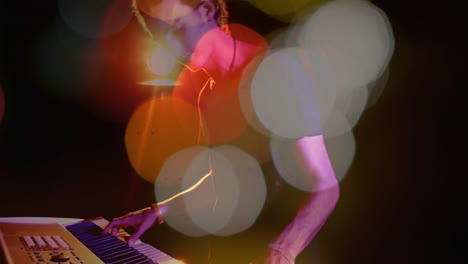 male musician playing electronic keyboard on dark stage, showcasing music tech with bokeh flares