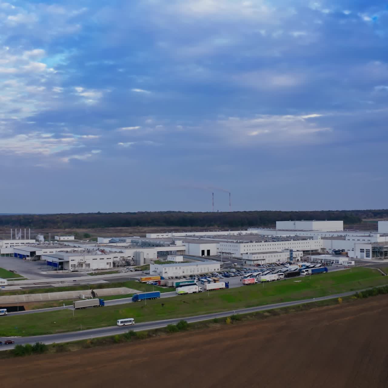 Modern plant under blue sky. Huge territory of industrial complex surrounded by beautiful nature. Pollution of the environment.