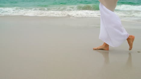 vista lateral de una mujer caucásica caminando por la playa 4k