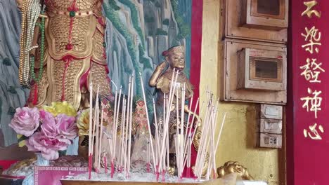 sacred serenity: chao mae sam muk shrine with incense lit before a golden buddha statue