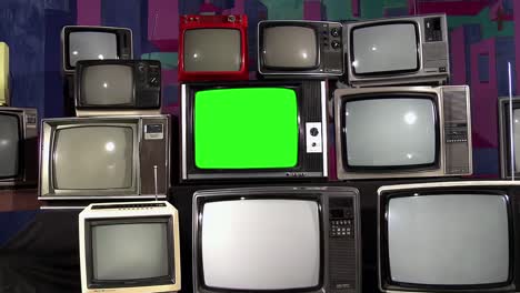 an old vintage television with green chroma key screen piled amidst many retro tvs. zoom in. 4k.