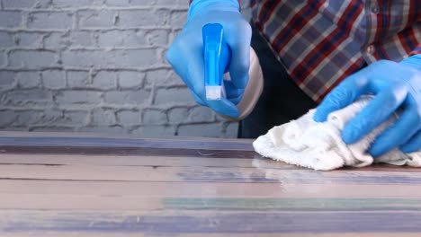 cleaning a wooden table with gloves