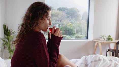 relaxing in bed, woman enjoying hot beverage in cozy home setting
