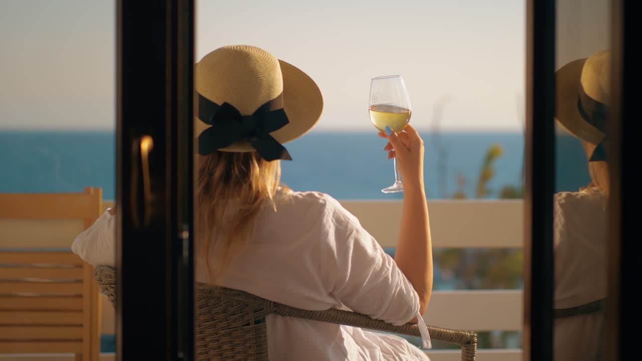 Woman having good time drinking wine at the balcony overlooking sea