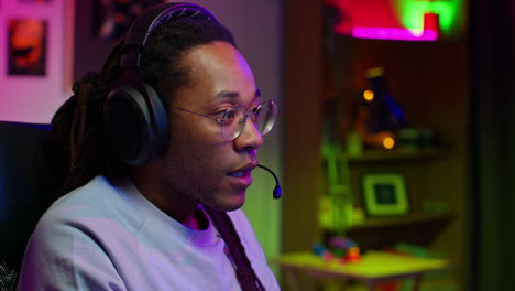 a young man with headphones and a microphone is playing a video game. he is focused and determined.