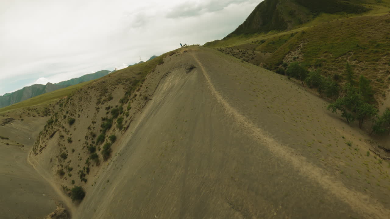 pista de tierra y motociclista descansando en la cresta de la colina fpv. deportista con motocicleta profesional termina la ruta en la cumbre de la montaña. deporte extremo afición
