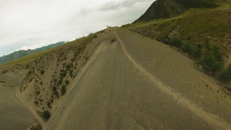 dirt track and resting motorcyclist on hill ridge fpv. sportsman with professional motorbike finishes route on mountain summit. extreme sport hobby