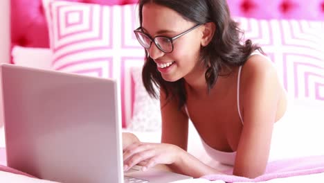 mujer atractiva acostada en la cama usando su computadora portátil