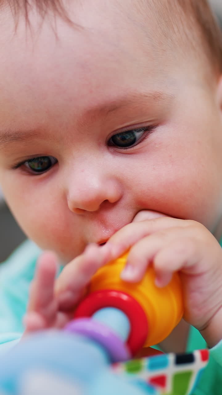 Darling little boy is busy playing with his toy. Child lies on belly waving with a toy. Close up. Blurred backdrop. Vertical video