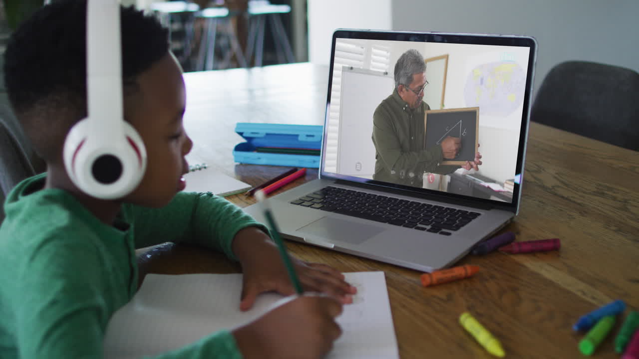 African american boy sitting at desk using laptop having online school lesson