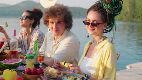 portrait of young male and female friends at lake party