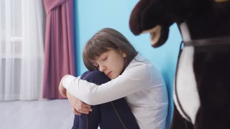 la niña de ojos azules está sentada sola en su habitación, infeliz y aburrida.