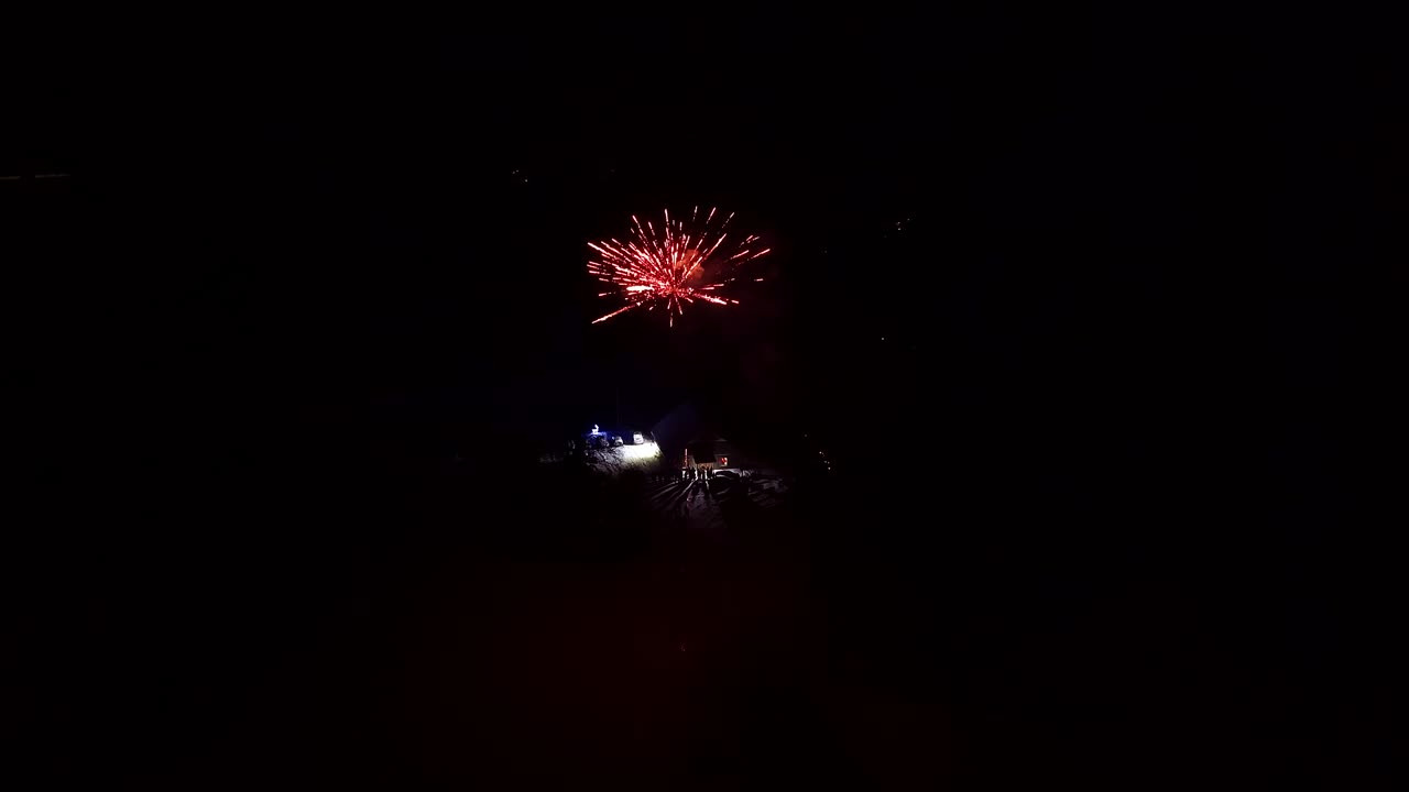 Fuochi d'artificio colorati che esplodono sopra un paesaggio innevato di notte.