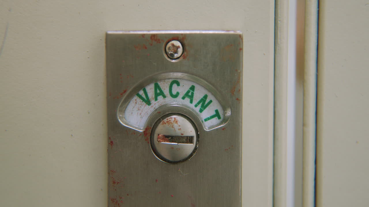 Slow motion close-up of bathroom stall lock changing from "Vacant" to "Engaged