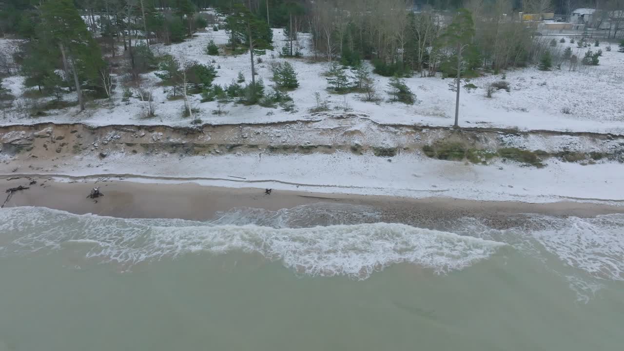 Aerial view of abandoned seaside fortification buildings at Karosta Northern Forts on the beach of Baltic sea , overcast winter day, wide drone dolly shot moving right