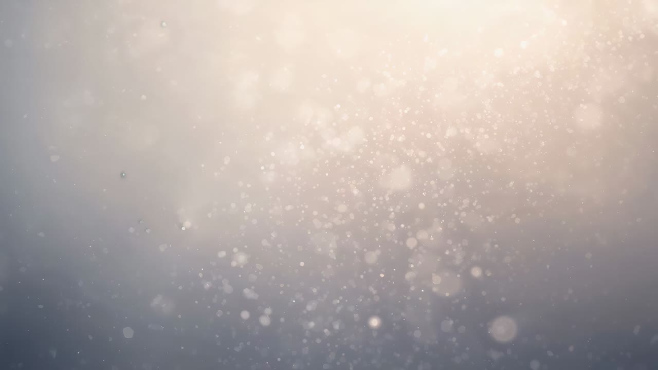 Drifting bokeh particles settling inward after warm highlight bloom in studio, with haze flares