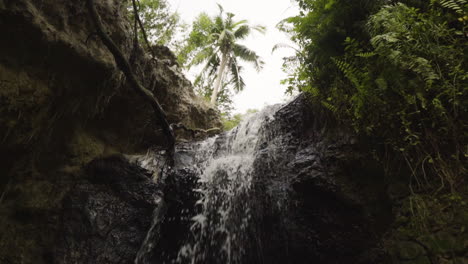 slow mo, water flowing down small tropical waterfall