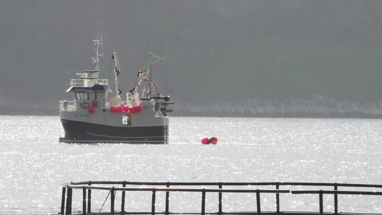 Fisherman On Fishing Trawler Floating In The Ocean Pulling The Bouy In The Ocean