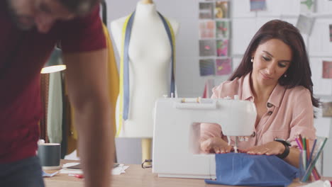 male and female fashion designers with sewing machine working in studio together