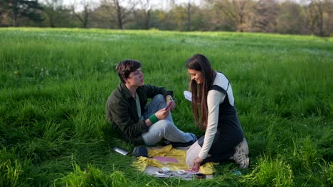 couple playing cards at a picnic in the park