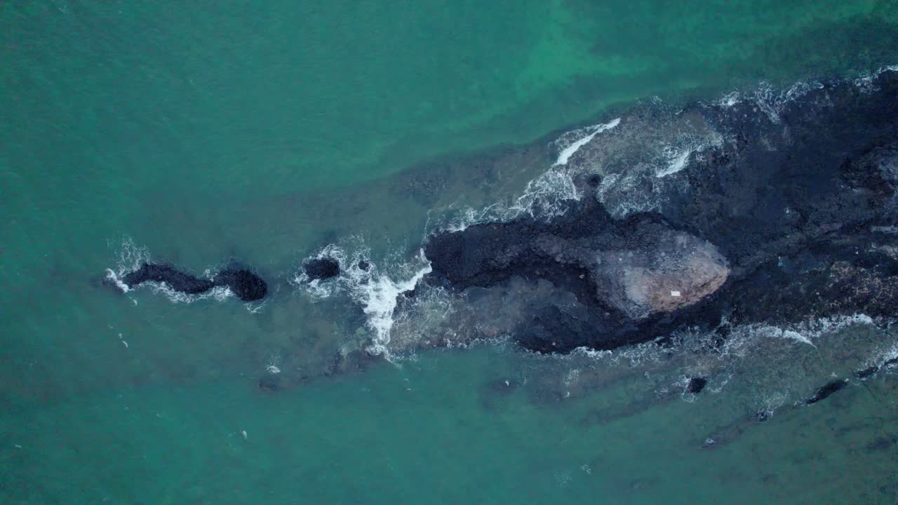 화산 폭발로 생긴 검은 바위에 부딪히는 파도의 평면도