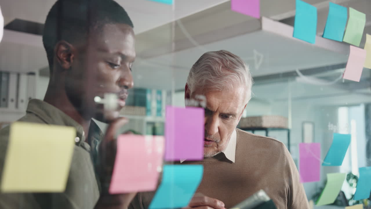 Businessmen Brainstorming with Sticky Notes on Glass Board