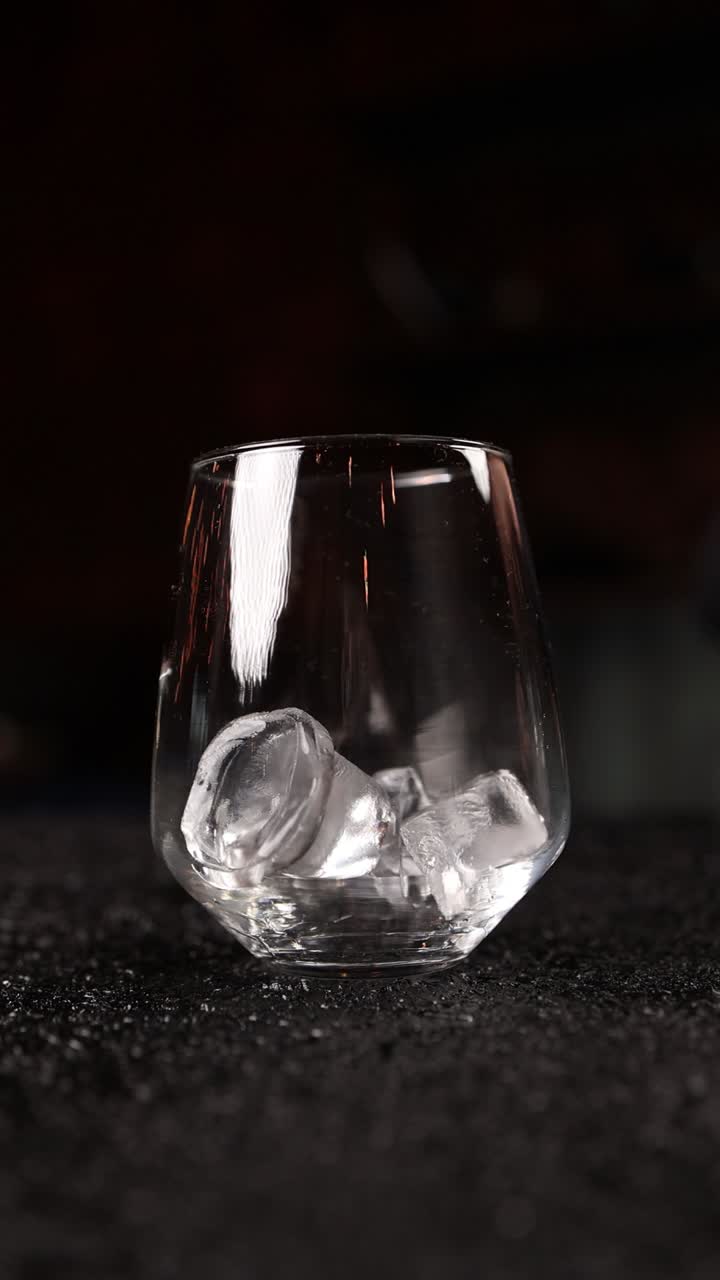 el camarero añadiendo hielo a un vaso de cóctel