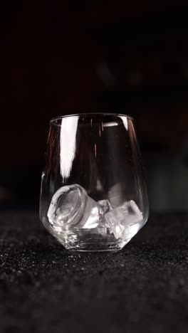 bartender adding ice to a cocktail glass