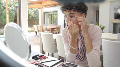 applying makeup, non binary person using eyeliner at home with cosmetics on table