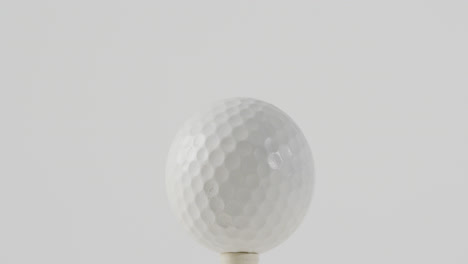 Nahaufnahme-Von-Golf-Tee-Und-Ball-Auf-Weißem-Hintergrund,-Kopierraum,-Zeitlupe