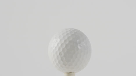 primer plano del tee de golf y la pelota sobre un fondo blanco, espacio de copia, cámara lenta