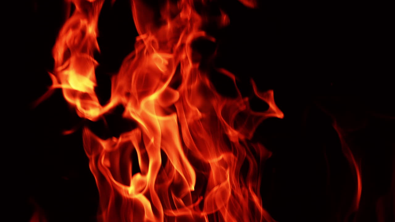 Tongues of flame burning at night. Isolated fire swaying in the wind in darkness.