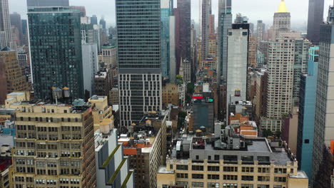 aerial view flying in middle of buildings in midtown, cloudy day in new york city