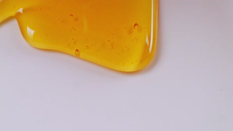 líquida y miel fresca goteando en el fondo blanco. saludable miel orgánica gruesa primer plano, dulce postre de miel 4k. cámara lenta