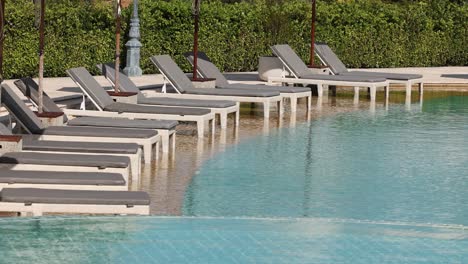 empty sun loungers by a tranquil pool
