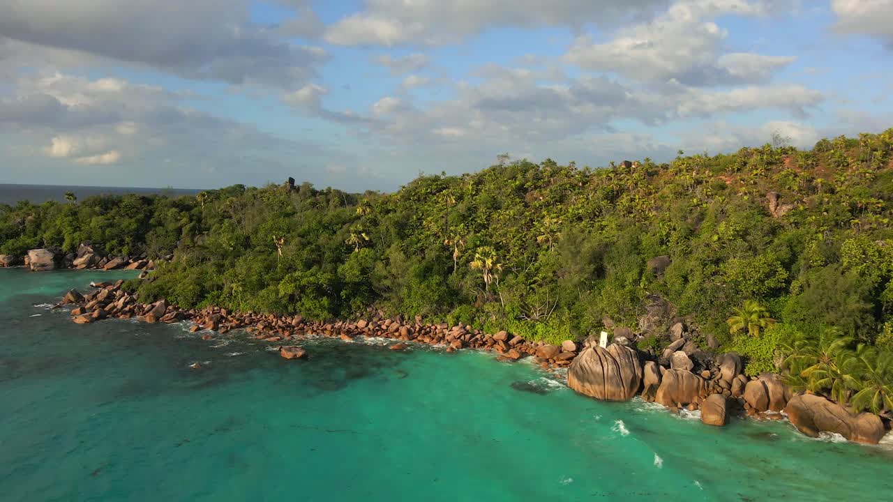 Krajiny na Seychelách natočené dronem shora, ukazující oceán, skály a palmy.
