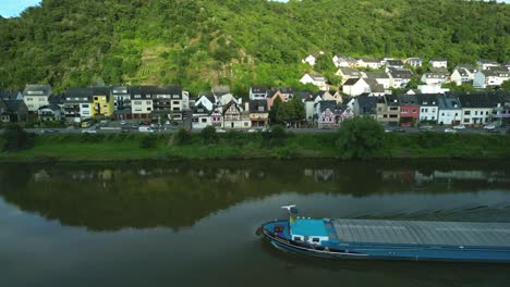 barge navigating the moselle river alongside a scenic german village