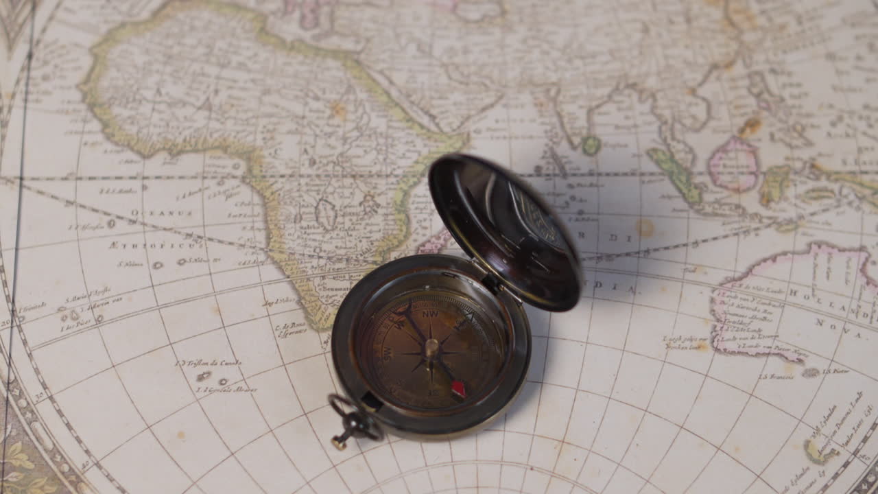 An atique brass compass on a vintage world map