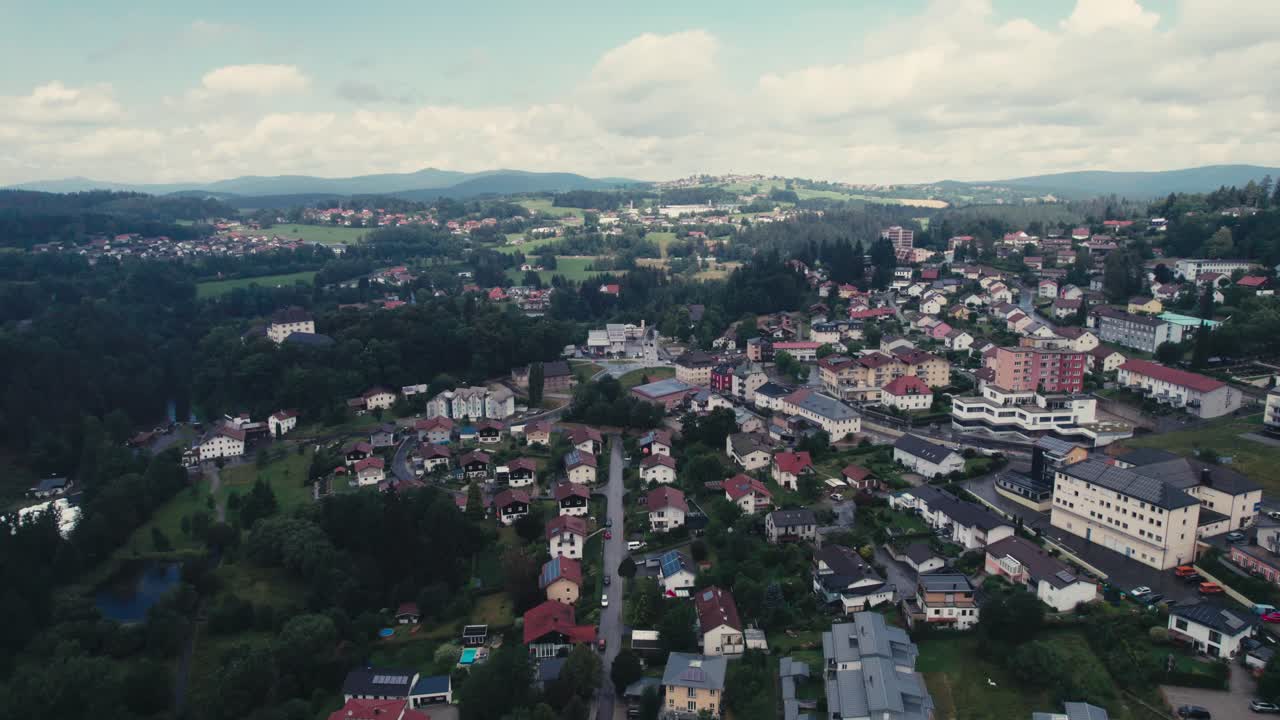 A quaint town with houses and greenery during daytime, cloudy sky, aerial view