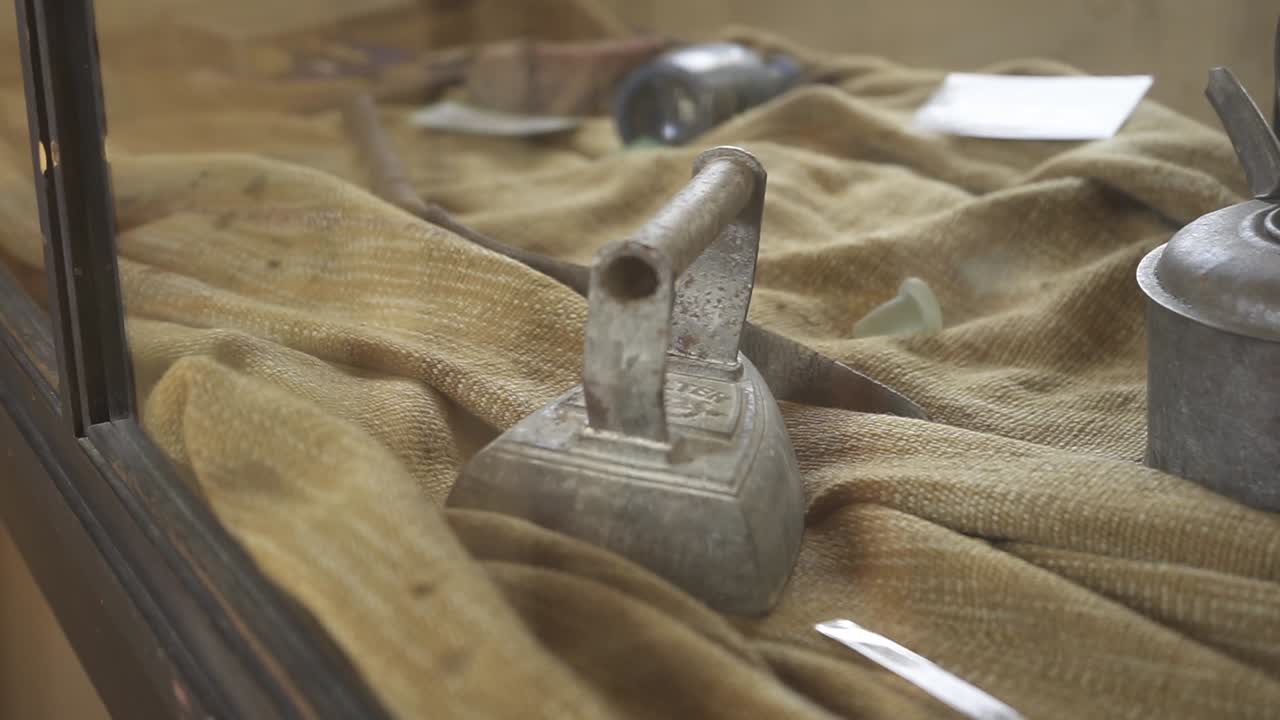 Vintage iron resting inside protective glass display, capturing nostalgic essence of historical domestic household technology and traditional living spaces