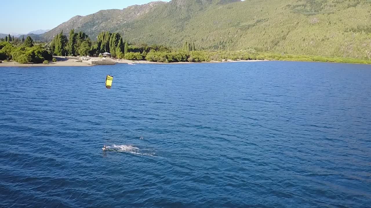 Aerial slow motion of a person practising kitesurfing at Puelo Lake, mountains in background, Patagonia Argentina
