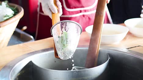 pouring broth into a bowl with noodles