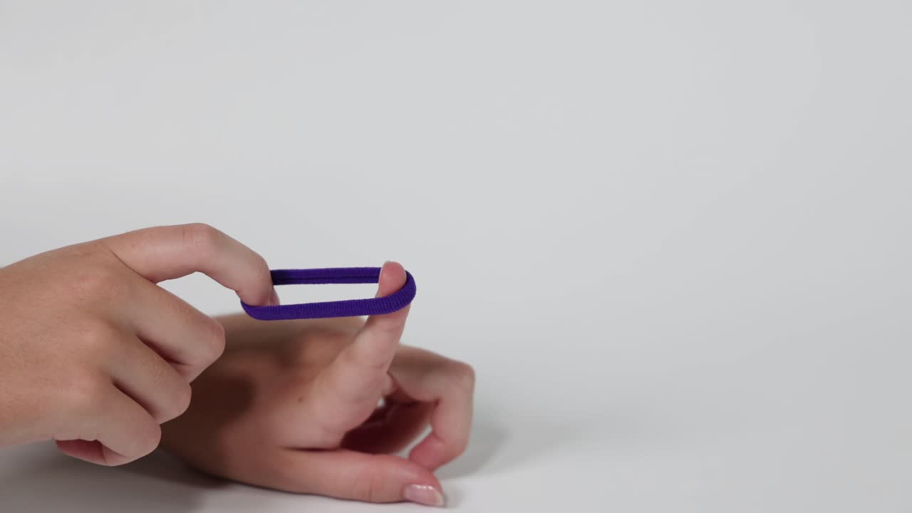 Hand flinging a purple hair tie