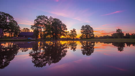 Stunning-purple-and-pink-sunrise-over-calm-country-farm-and-pond,-amazing-clouds