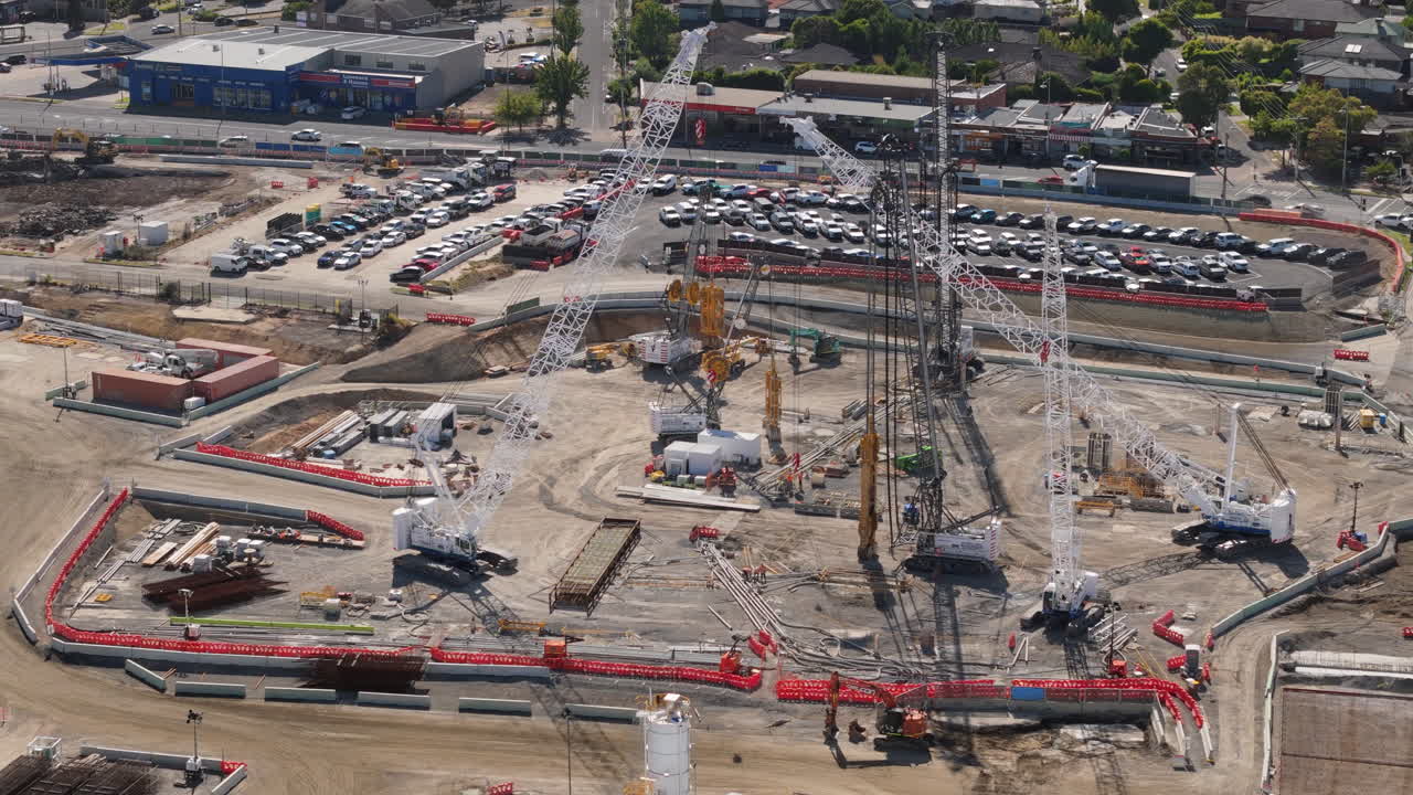 Trave aérea passando por guindastes imóveis em um grande projeto de construção de túnel. Nos arredores do centro de Melbourne, este grande projeto se desenvolve entre os subúrbios urbanos.