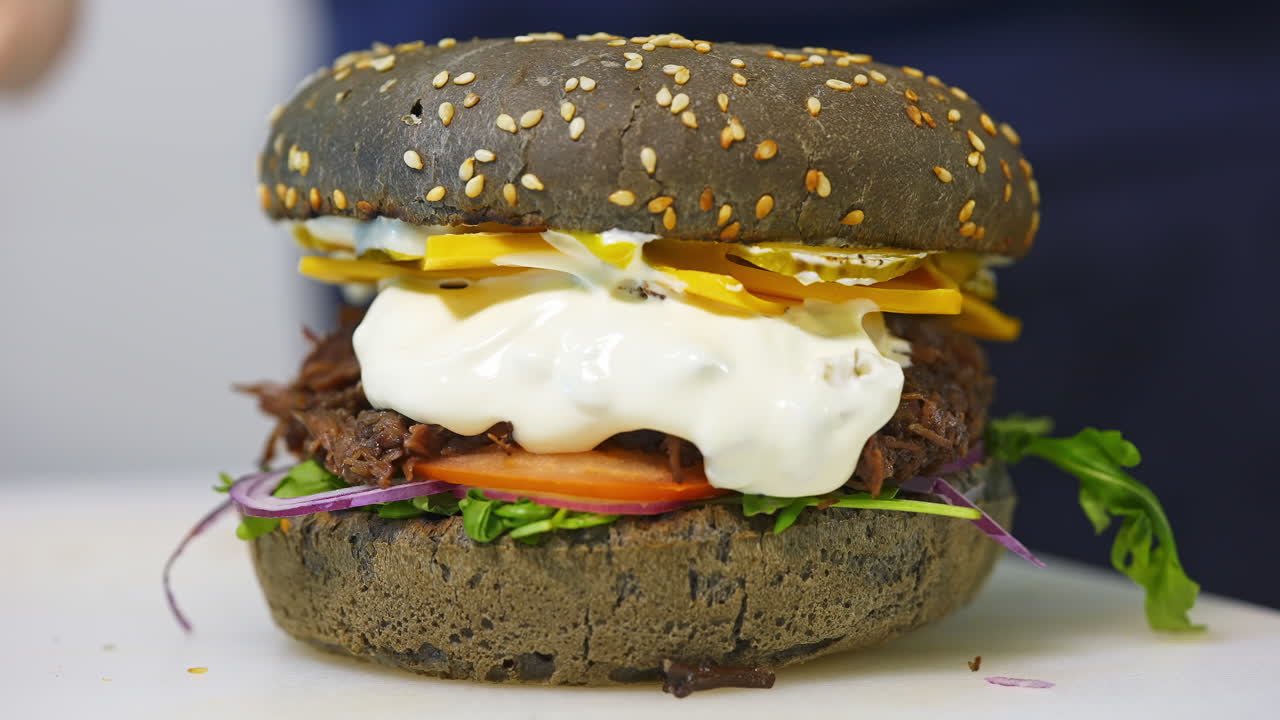 Tasty brown burger prepared by a professional chef. Burger prepared. Fresh tasty burger with cheese and vegetables. Close-up.