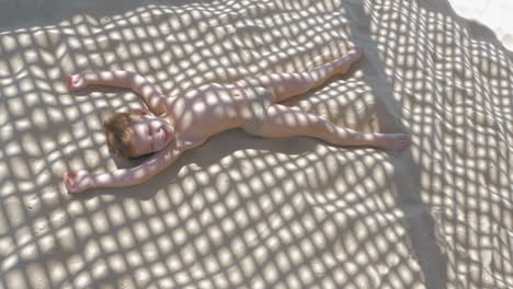 child making sand angel when relaxing on the beach