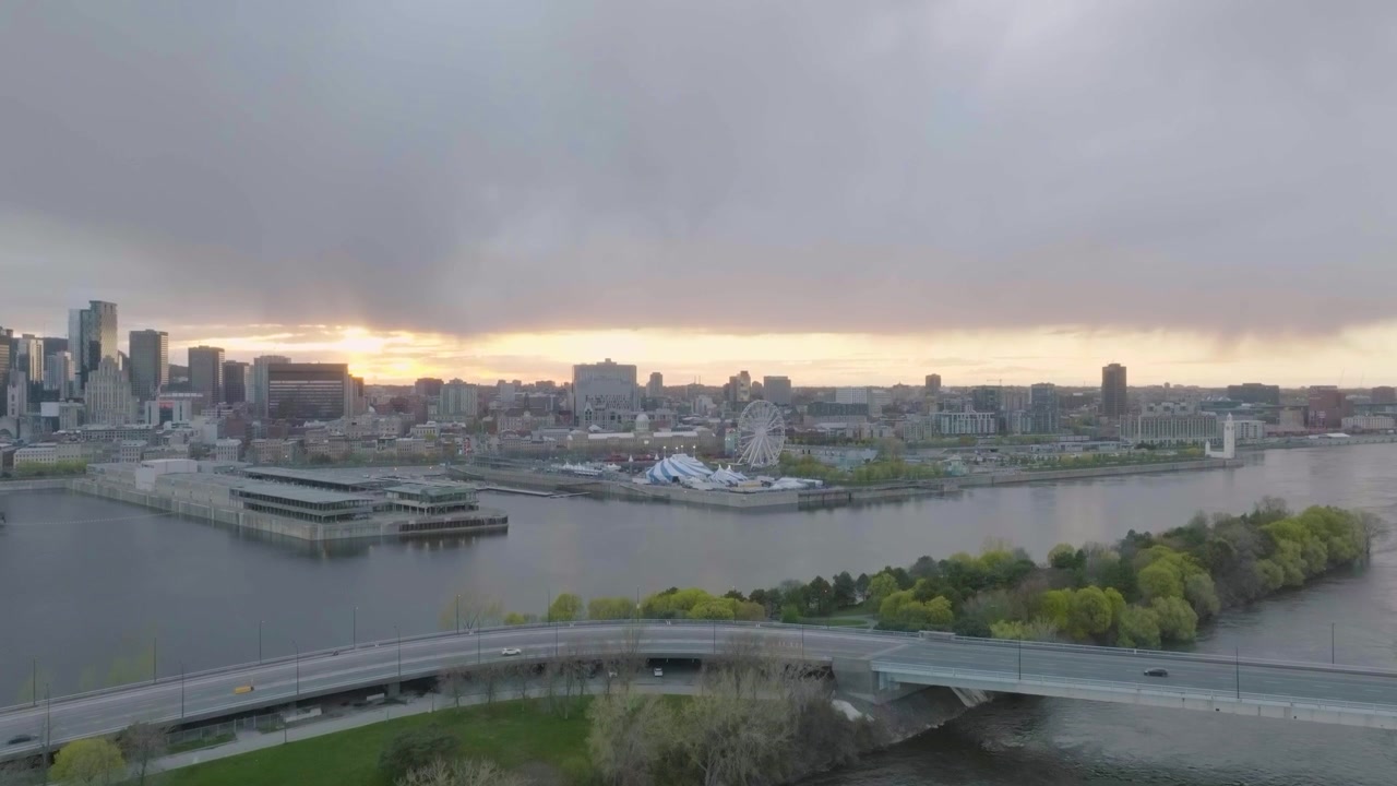Movimento laterale del drone che domina principalmente la città di Montreal nel vecchio porto, Cirque du Soleil, edifici portuali e sole sullo sfondo