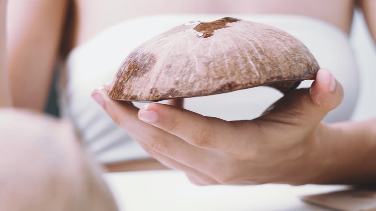 крупный план женщины, занимающейся обработкой скорлупы кокосового ореха на балконе дома
