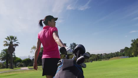 caucasian woman playing golf carrying bag filled with golf clubs